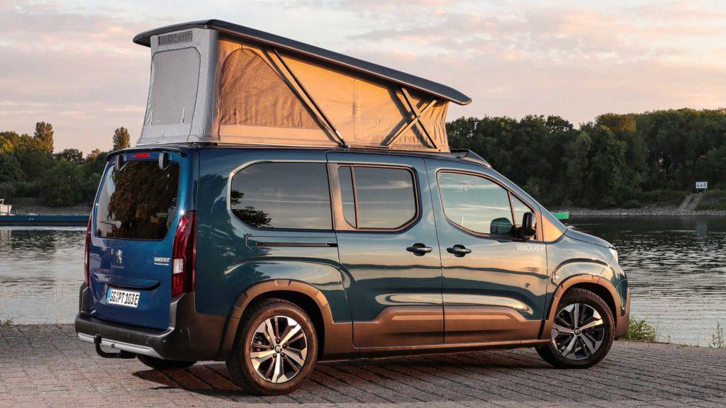 Rein elektrischer Camper-Van Peugeot E-Rifter Vanderer vor Gewässer im Sonnenuntergang und mit ausgestellten Dach