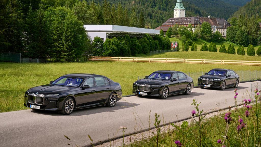 Drei schwarze Luxuslimousinen BMW i7 als gepanzerte Version vor grüner Dorf-Kulisse