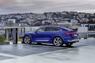 Elektroauto Audi Q8 e-tron Sportback in blau beim Laden vor Städtelandschaft