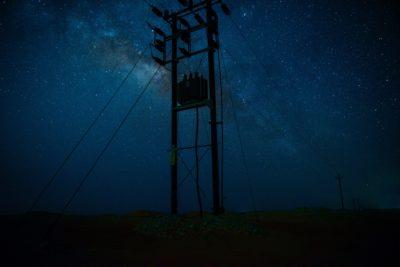 Strommast bei Nacht vor einem Nachthimmel